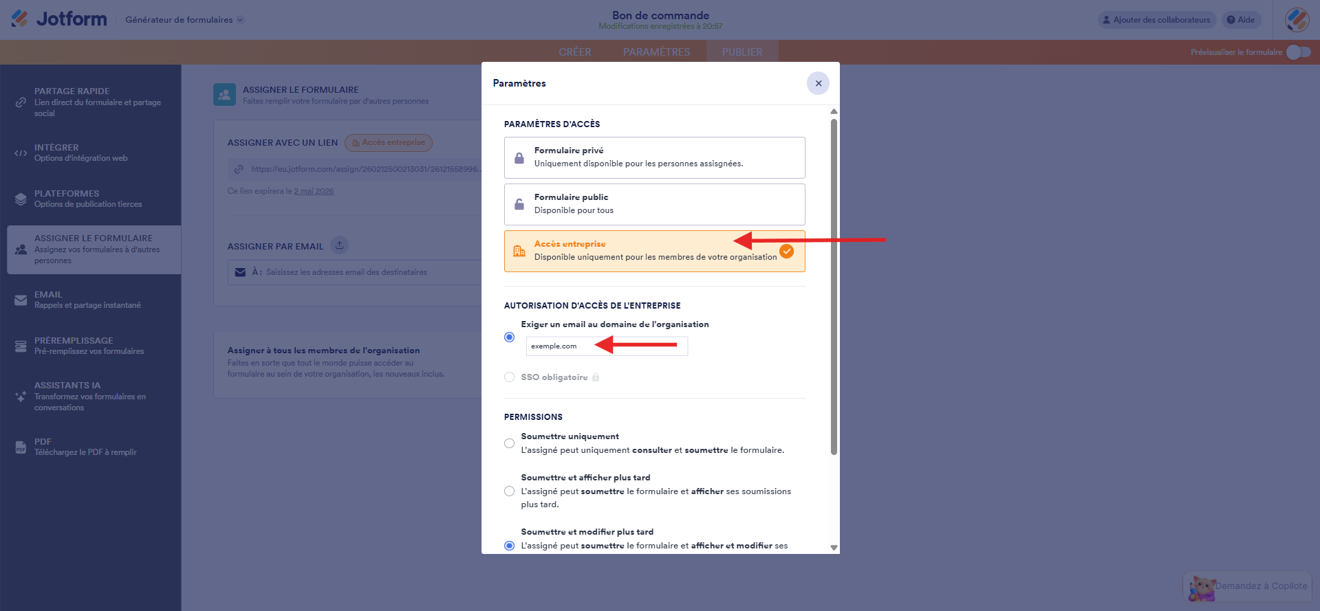 Capture d'écran de la fenêtre modale Paramètres dans le Générateur de formulaires Jotform avec une flèche vers Accès entreprise et une autre vers le champ de la section Exiger un email au domaine de l'organisation avec le nom de domaine exemple