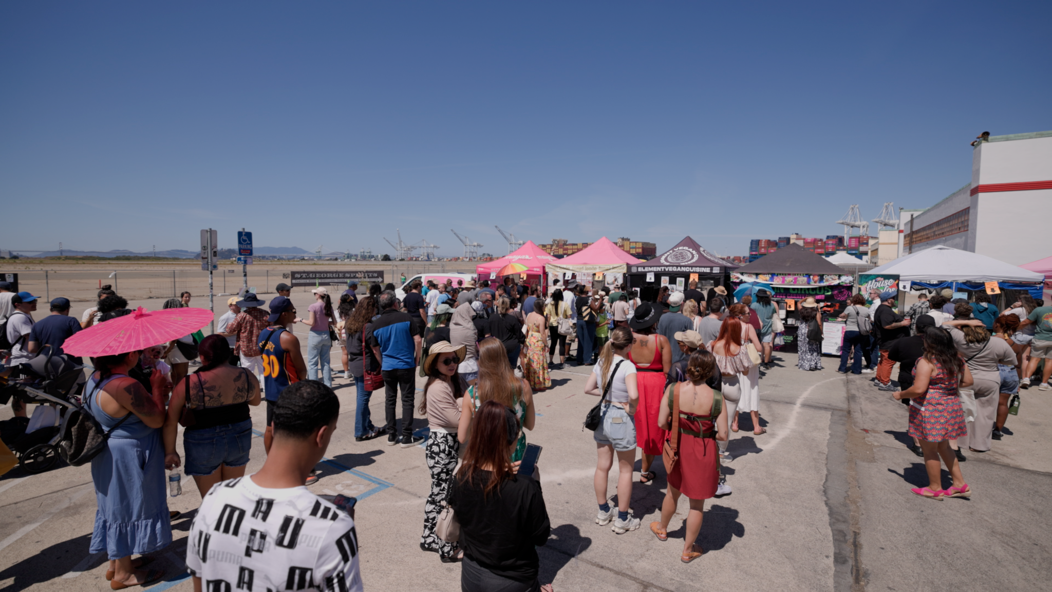 A wide shot of a bustling outdoor event on a sunny day with clear blue skies